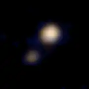 Image en vraies couleurs de Pluton (l'objet le plus brillant) et Charon, prise par New Horizons, le 14 avril 2015.