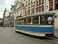 Un tramway ancien crème à bande bleue en circulation.