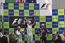 Photo du podium du GP d'Espagne, avec Button entouré de Barrichello et Webber, applaudis par les officiels de l'épreuve