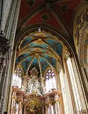 Photographie d'un chœur d'église richement orné et éclairé par de vastes fenêtres.