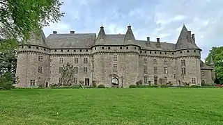 façade d'un château fort à tourelles, sous le soleil.