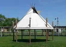 Photographie d'un « cercle de pow-wow » figurant un tipi suspendu.