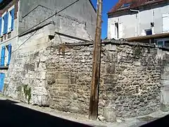 Vue d'un mur en pierre le long de deux maisons.