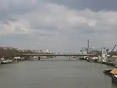 Photo du pont aval franchissant la Seine. À droite une barge transportant des matériaux et une zone industrielle