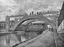 le canal de l'Ourcq avec au deuxième plan le pont en position basse avec une locomotive à vapeur qui le traverse