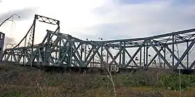 Le pont Alphonse-XIII en 2008, démonté et abandonné dans un pré à l'entrée du portLes coordonnées indiquées ici sont celles de l'emplacement originel du pont, et non de celui où il se trouve entreposé depuis 2003..