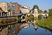 Pont et quai adjacent et leur reflet dans le cours d'eau.