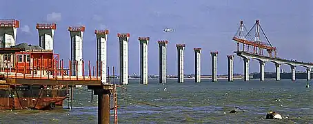 Construction du pont. La poutre de lancement de manipulation des voussoirs mesurait 285 m de long. Elle fut démontée sur l'île à la fin des travaux.