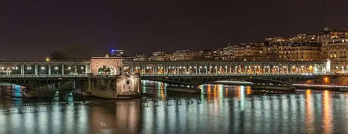 Nombreuses petites lumières partout, des arches plongent dans l'eau, soutenant une colonnade. Ces lumières se reflètent dans l'eau du fleuve, lui donnant une lumière bleue dans la nuit.