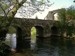 Photographie montrant un pont de pierres à trois arches enjambant un cours d'eau.