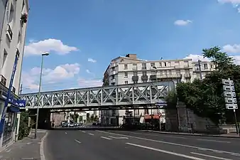 Photographie en couleur d'un pont ferroviaire surplombant une rue.