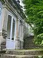 Latéral de la façade avec l'escalier et la porte.