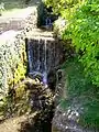 La cascade en bas de la rue de la Cascade, à l'angle avec la rue du Moulin ; apparemment en rapport avec un ancien moulin.