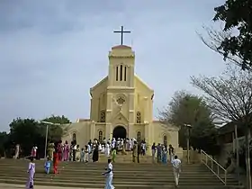 Plusieurs dizaines de personnes devant une église aux tons jaunes.