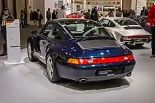 Porsche 993 Targa bleue, vue de 3/4 arrière. La plaque d'immatriculation indique "Porsche Classic Partner".