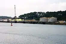 Photo d'un cours d'eau avec des unités circulaires de stockage et du soufre sur la rive.