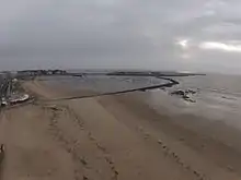 Le port d’échouage est aménagé sur la partie orientale de la plage des Libraires, en survol de laquelle est pris ce cliché. En arrière-plan, à droite, le port en eaux profondes, relié à la pointe du Bec par un viaduc. (Vue hivernale).