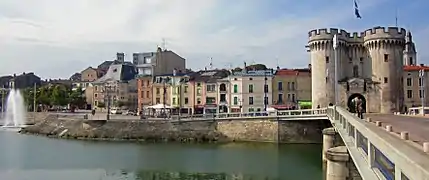 Pont enjambant un fleuve et porte de remparts au bout.