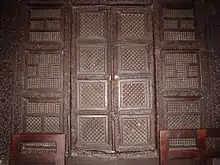 Photographie de la porte à deux battants de la maqsura. Chaque vantail possède quatre panneaux ajourés de forme carrée.