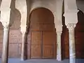 Vue centrée sur l'une des portes en bois sculpté de la salle de prière. Sa décoration comprend des moulures et des motifs géométriques simples (rectangles, carrés, etc.).