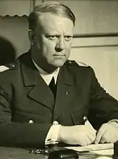 Portrait en noir et blanc d'un homme blond en uniforme assis à un bureau