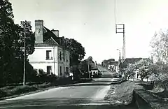 Photographie en noir et blanc d'une route et d'un établissement postal.