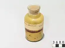 Photographie d'un pot en verre rempli d'un liquide jaunâtre.