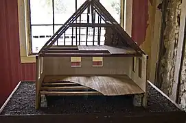 Coupe d'une maquette de maison avec poteaux en terre.