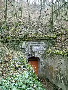 Passage entre deux murs vers une porte, sous le niveau du sol