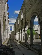 Ruelle située entre une arcade et un mur tous deux de style roman.