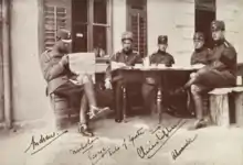 Photographie montrant cinq soldats assis autour d'une table.