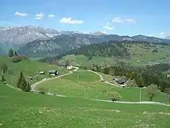 Prairies et fermes au niveau du lieu-dit « Les Molliettes ». Au fond la chaîne des Aravis.