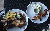 À gauche : homard tandoori avec frites et légumes. À droite : crevettes tandoori avec sauce.