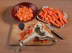 Carottes découpées disposées dans des plats avec planche de travail.