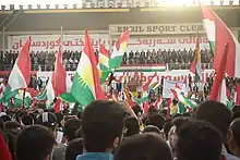 Rassemblement d'individus agitant des drapeaux du Kurdistan irakien