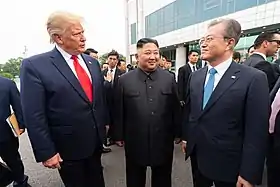 Trump (à gauche), Kim (au centre) et Moon (à droite) discutant ensemble dans la zone démilitarisée.