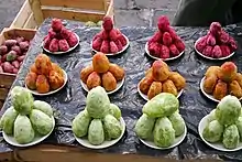 Des figues de barbarie pelées, de couleur verte, jaune ou rouge, empilées dans des coupelles sur un étal de marché