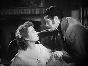 Laurence Olivier (à droite) se penche vers Greer Garson dont il serre une main