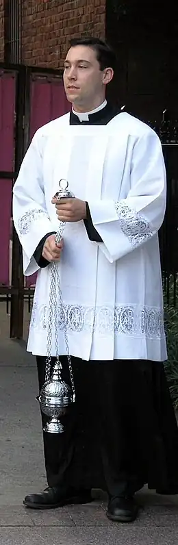 Un thuriféraire portant un surplis blanc.