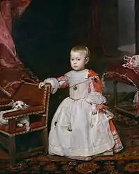 Un très petit enfant, noblement vêtu en blanc, debout sur fond d'intérieur de couleur dominante rouge