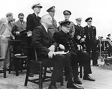 Churchill et Roosevelt lors du service religieux, à bord du Prince of Wales. Au deuxième rang (debout) l'Amiral King, chef des opérations navales de l'US Navy.