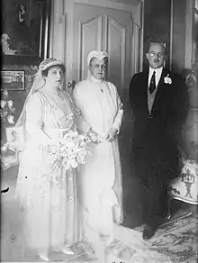 Portrait d'un couple en tenue de mariés et d'une vieille femme vêtue de blanc.