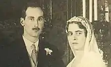 Portrait d'un homme moustachu en costume sombre et d'une femme portant un voile de mariée blanc.