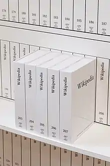 Plusieurs livres blancs à la typographie sobre, rangés verticalement, dont les tranches et la couverture de l'un d'entre eux sont lisibles