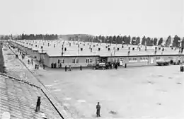 photographie en noir et blanc de baraquements vus de haut, un militaire au premier plan.