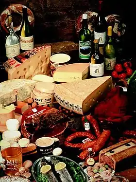 photographie représentant divers spécialités culinaire franc-comtoises dont les saucisses de Morteau et Montbéliard, des fromages tels le comté, la cancoillotte, le mont d'or et des vins du Jura