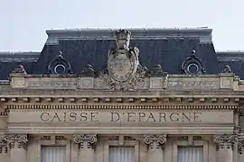 Détail de la partie supérieure de la façade principale avec l'inscription du nom et le blason de la ville.