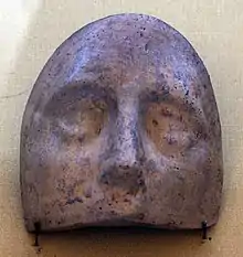 Partie haute d'un masque ovale en céramique où sont visibles les yeux et le nez.