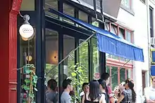 Une dizaine de personnes attendent devant l'entrée du restaurant Prune à New York, dont l'enseigne est visible au premier plan