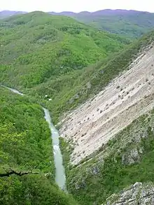 Une rivière coulant entre deux massifs montagneux et boisés.